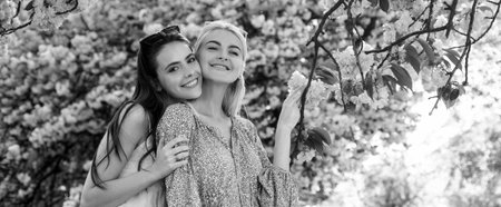 Spring banner with women girlfriends outdoor. Two young women relaxing in sakura flowers. Spring girls.の写真素材