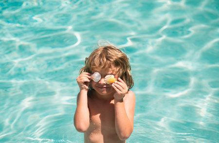 Swimming, summer vacation, lovely child boy playing in blue water. Covered eyes with shells.の写真素材