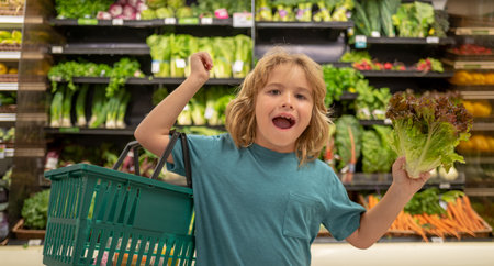 Child with lettuce salad. Funny cute child on shopping in supermarket. Grocery store. Grocery shopping, healthy lifestyle concept.の写真素材