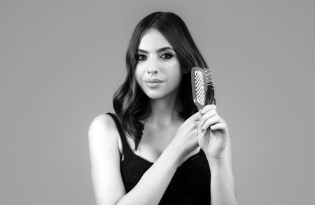 Close up portrait of happy beautiful girl with shiny hair with comb. Attractive smiling woman brushing hair.の写真素材