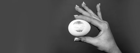 Easter banner. Print of red lips on white egg. Red lip imprint on easter egg on red background. Lipstick kiss print.の写真素材