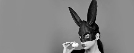 Easter banner with bunny woman. Woman rabbit, easter bunny girl. Red lip imprint on easter egg on red background. Female mouth kiss. Print of red lips on white egg.の写真素材