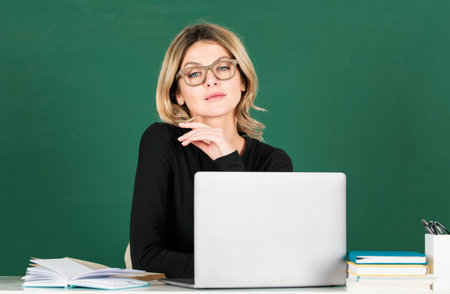 Portrait of teacher or female tutor working at table in school. Young women student studying in class.の写真素材