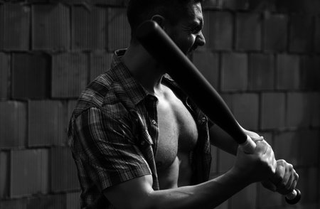 Brutal angry gang man lifestyle, serious handsome guy. Aggressive man with baseball bat for fighting. Dangerous man with serious emotion.の写真素材