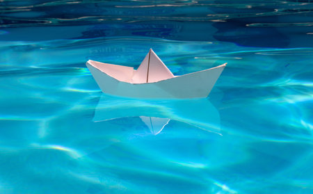 Origami ship. White paper boat into the clear sea water.