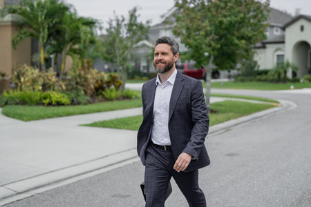 Business man walk near house in american neighborhood. Business man walk down street, late for a...