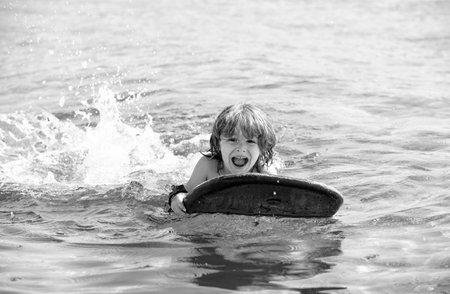Summer vacation. Child with surf board. Summertime. Smiling boy swimming.