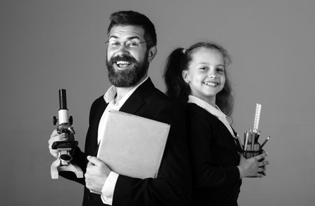 Amazed teacher with excited happy pupil school girl. Portrait of funny pupil schoolgirl and tutor with school supplies. Happy teacher and student girl isolated on gray background. Back to school.の写真素材