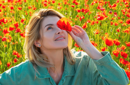 Woman in a field of red poppies enjoys nature. A young woman in a poppy field. Spring girl.の写真素材