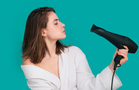 Young woman using hair dryer. Hairstyle, hairdressing concept.の写真素材