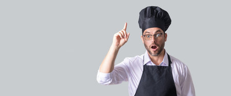 Handsome male chef cook or baker man in apron, shirt and cooking hat isolated on gray background. Cooking food concept. Mock up copy space. Chef Man in chef hat. Isolated banner of man cooking.の写真素材