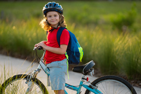 Boy in a helmet riding bike. Boy in safety helmet riding bike in city park. Child first bike. Kid outdoors summer activities. Kid on bicycle. Little child riding bike in summer park on a driveway.の写真素材