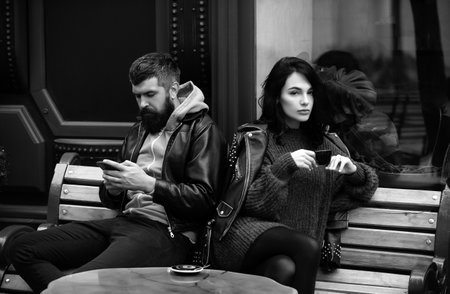 Young couple sitting after a fight. Sad woman after quarrel with boyfriend. Angry couple ignoring...