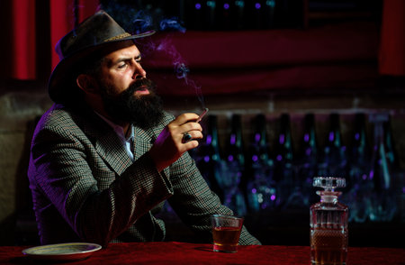 Portrait of a handsome bearded man, with a glass of alcohol in his hands. Rest and relaxation.の写真素材