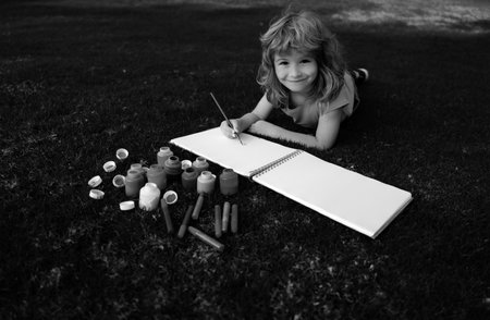 Kids painting with paints color and brush in park outdoor. Happy child playing outside. Drawing...
