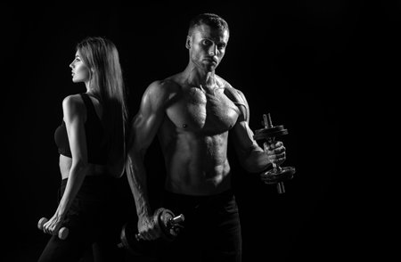 Sporty sexy couple with dumbbells on black studio background. Muscular sexy couple body.の写真素材