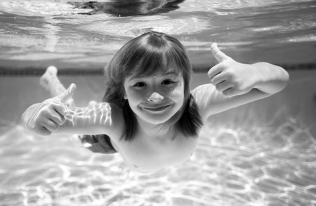 Underwater child swims in pool, healthy child swimming and having fun under water. Summer vacation.の写真素材