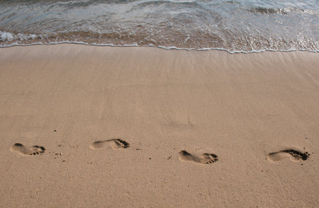 Footprints at golden sand, footsteps. Sea background, nature of tropical summer beach with rays of...