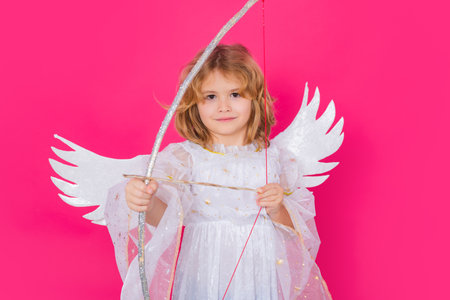 Cupids arrow hit right in heart, arrow of love. Angel kid shoots a love arrow from a bow on Valentines Day. Christmas kids. Little cupid angel child with wings. Studio portrait of angelic kid.の写真素材