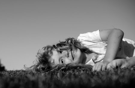 Portrait of a happy smiling child boy playing on grass field outdoor. Laughing child. Expressive facial expressions.の写真素材