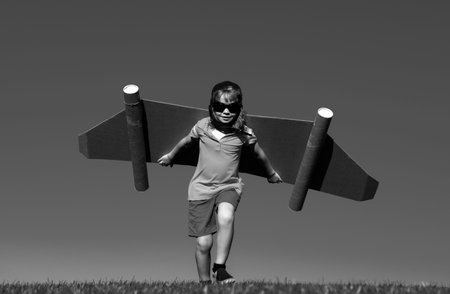 Kid with jet pack superhero. Child pilot against summer sky background. Boy with paper plane flight,...