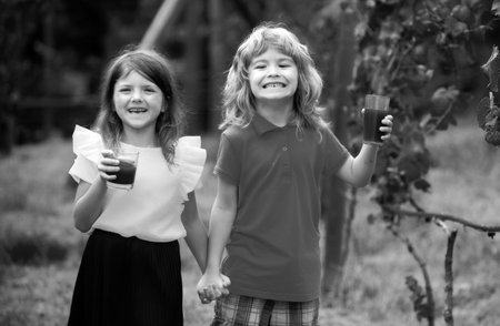 Two kids drink green smoothie outdoors at summer park. Brother and sister happy walking in nature....