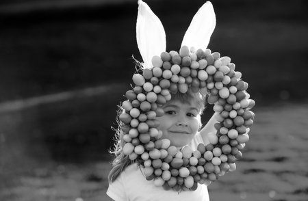 Child boy with easter eggs and bunny ears outdoor. Cute kid having happy easter in park. Funny kids face closeup.の写真素材