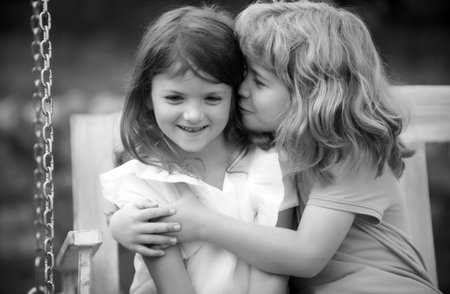 Two little children hug and kiss each other in summer garden. Kids couple in love. Friendship and childhood. Happy children having fun outdoors. Kids playing in spring park. Shy girl.の写真素材