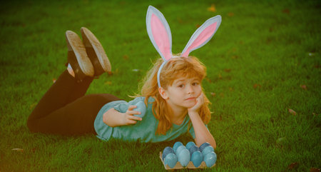 Child boy hunting easter eggs. Cute kid in bunny ears having fun in park. Easter egg hunt concept.