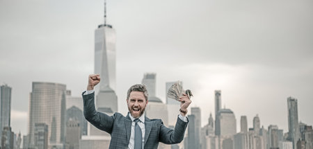 Businessman hold money in New York. Businessman with dollars outdoor. Wealth rich businessman millionaire in suit holding money. Excited business man winner celebrating success. Finance and banking.の写真素材