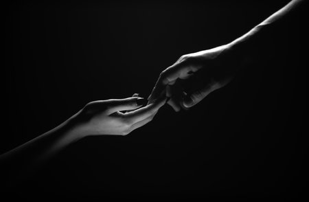 Two hands reaching toward. Tenderness, tendet touch hands in black background. Romantic touch with fingers, love. Hand creation of adam.の写真素材