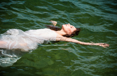 Young sexy woman is swimming in the transparent, blue sea. Sensual slim woman floating on the water of ocean water.の写真素材