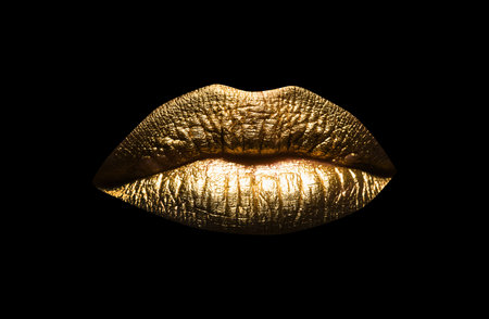 Closeup sexy beautiful female golden lips isolated. Gold lipstick. Gold lips. Gold Paint from the lips. Golden lips on beautiful model girls mouth.の写真素材