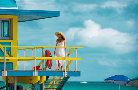 Beautiful woman walking on the miami south beach. Girl walk near miami beach lifeguard.の写真素材