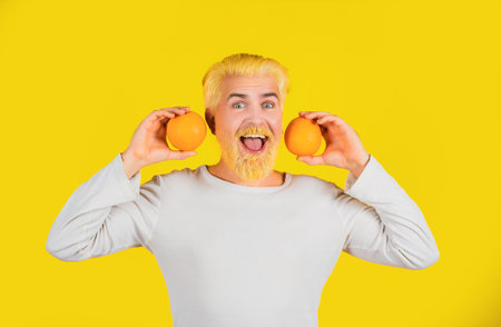 Man with orange fruit on orange background. Close up portrait young man holding sliced orange.の写真素材