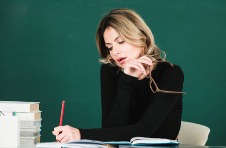 Pretty young high school or college teacher on the chalkboard. Young caucasian female business woman...