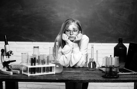 Funny sad schoolgirl scientist in the laboratory. Chemical experiment. Funny schoolgirl kid doing experiments in the chemistry laboratory. Explosion in the lab. Science and education.の写真素材