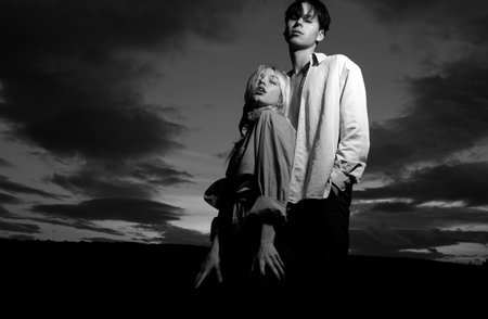 Young couple in love spends time together on dramatic sky. Man embracing and going to kiss sensual woman.の写真素材