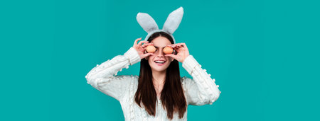 Easter banner. Funny woman wearing bunny ears and having fun with Easter eggs. Playing hunt eggs. Happy Easter concept.の写真素材