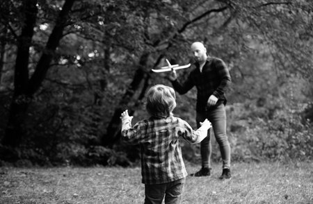 Cute child with dad play with toy plane. Fathers day. Dad and baby son playing together outdoors toy airplane.の写真素材