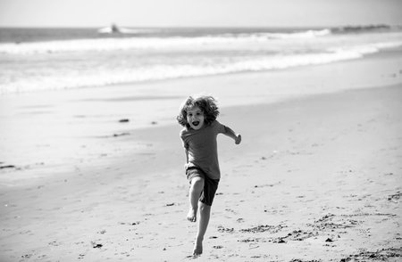 Child boy running and jumping in summer sandy beach.の写真素材