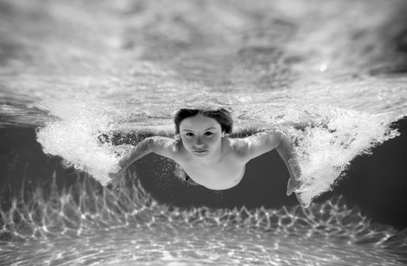 Child boy swim under water in sea. Kid swimming in pool underwater. Happy boy swims in sea...