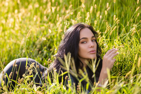 Sexy woman lying on grass. Summer beauty sexy woman outdoor portrait. Beautiful woman relaxing in the field with green grass.の写真素材
