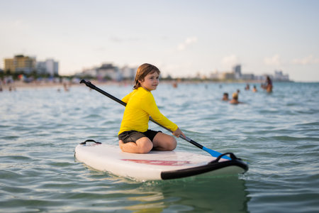 Child swimming on paddle board. Water sports, active lifestyle. Kid paddling on a paddleboard in the...
