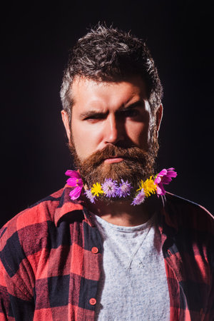 A bearded man with a decorated beard for the Spring holiday. Flower in the beard. Barber shop. Man hair beauty. Beard Care and Facial Hair. Beard Styles for barbers.の写真素材