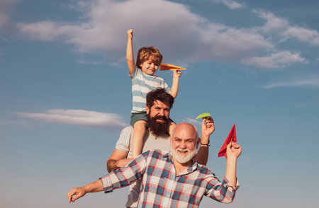 Happy child playing outdoors. Freedom to dream - joyful kid playing with airplane against the sky - vintage effect. Father son and grandfather relaxing together.の写真素材