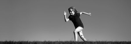 Banner with spring kids portrait. Happy kids playing and running on grass outdoors in summer park. Active kids healthy outdoor. Fun activity.の写真素材