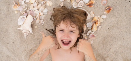 Happy Summer. Cute blonde child relax on sand. Child play with Sea shells and fine beach sand. Kid...