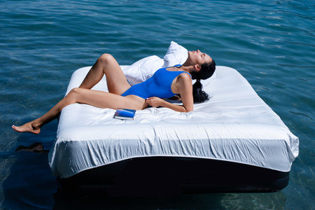 Comfort cozy bed concept. Woman with inflatable mattress in summer water. Sexy woman sleeping or resting on a mattress in the water. Water mattress concept. Sweet dreams. Summer rest.の写真素材