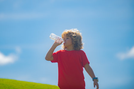 Portrait of little child with bottle of fresh water. Thirsty kid. Refreshing. Water balance. Close up portrait of kid drinking water in park. Portrait of child drinking waters.の写真素材